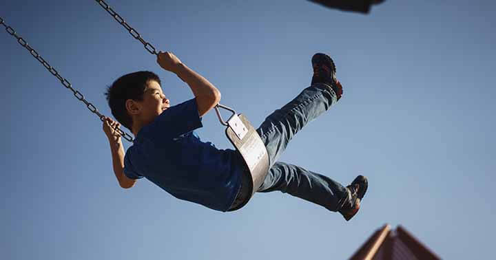 A happy boy swinging in the air