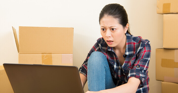 A lady using the laptop, surrounded by boxes at home