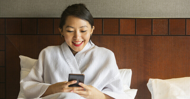 Excited lady using her phone in the hotel room
