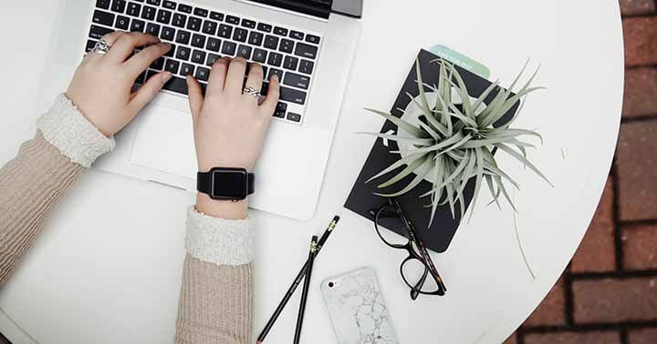 Flatlay image showing a pair of hands typing on the laptop