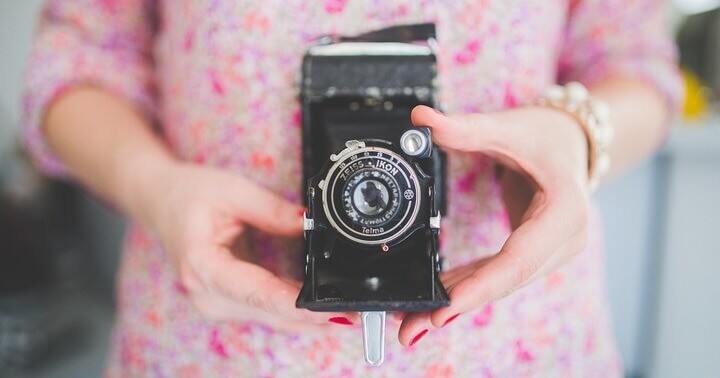 A lady holding onto a retro camera