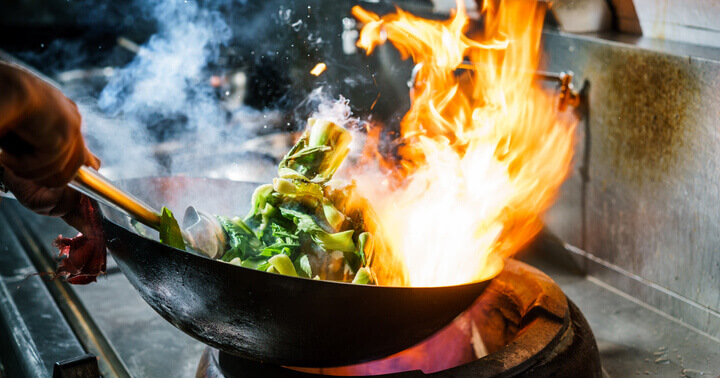 Charred food being cooked in the kitchen inside a wok