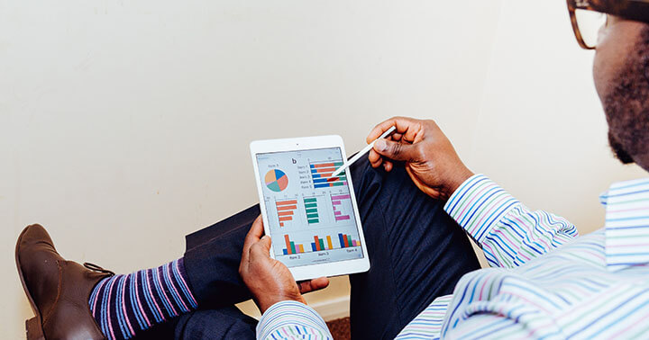 A man using an ipad with a screen showing charts