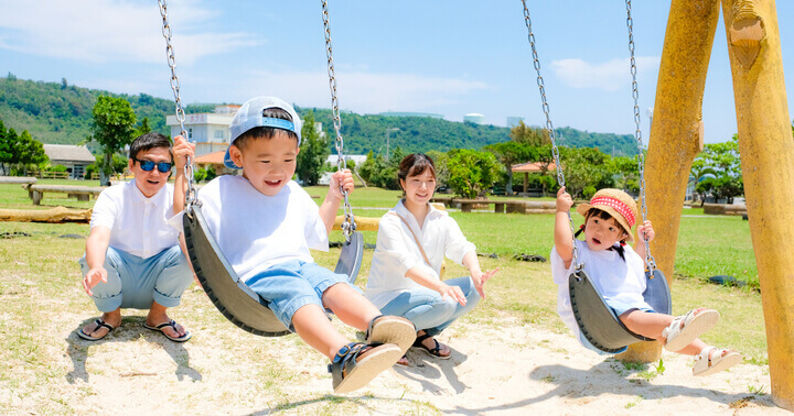 Parents pushing their children on a swing at the park