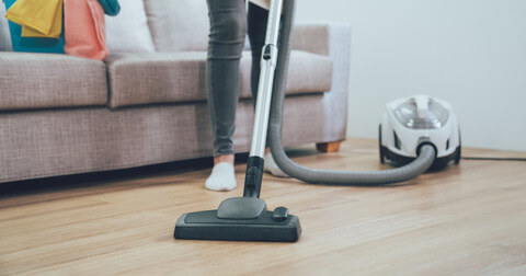 A domestic helper vacuums the floor