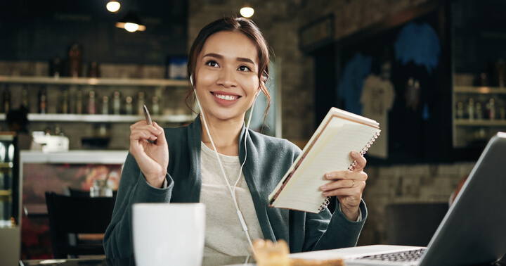 A cheerful young woman sitting in a cafe deciding on the different types of life insurance she will be getting