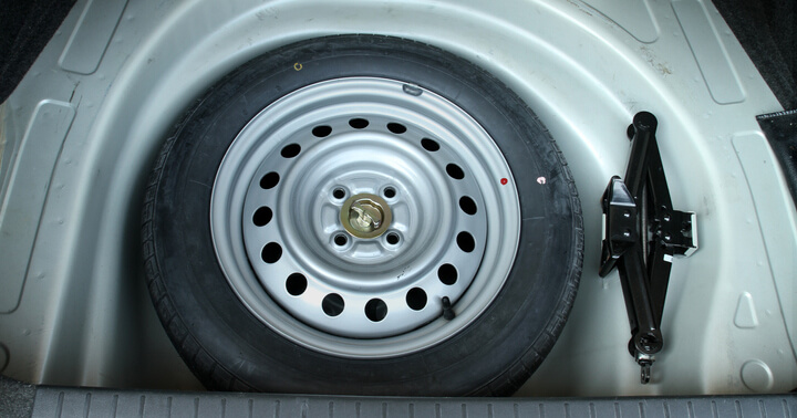 Spare tyre and car jack in the trunk of the car