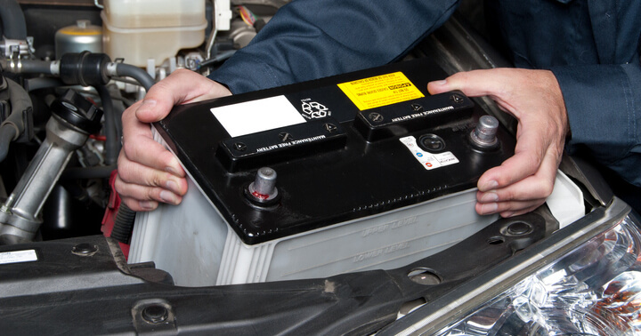 A person holding up the car battery