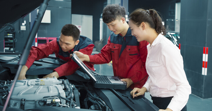 A couple of professional car mechanics consulting a lady on her car's performance