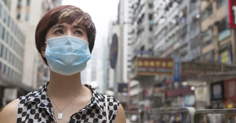 A woman wearing a face mask standing in a city in the middle of the coronavirus pandemic.