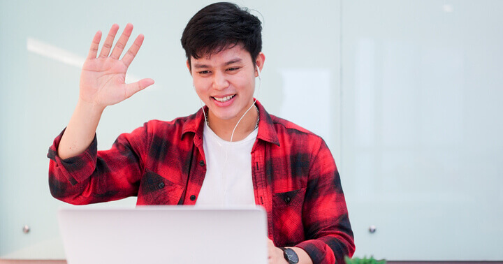 A young man working-from-home and communicating with his colleagues online during the coronavirus pandemic