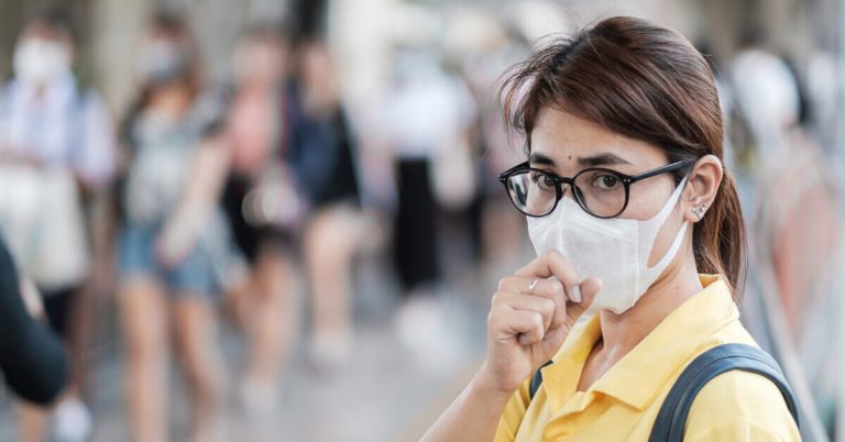 a woman with a face mask social distancing from other people while in public