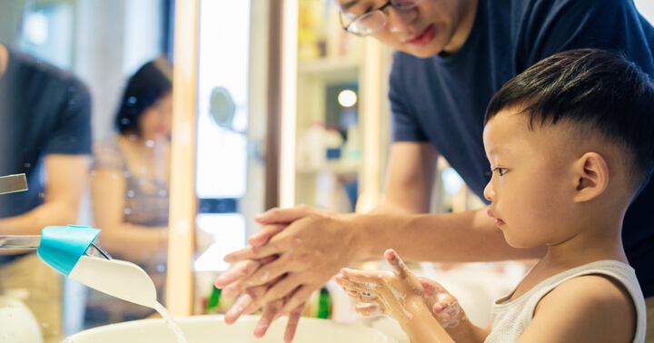 A father and son washing their hands at the bathroom sand with water and soap