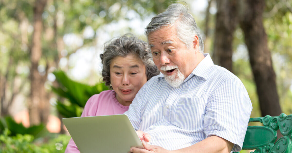 An old couple looking at the ipad in the outdoors