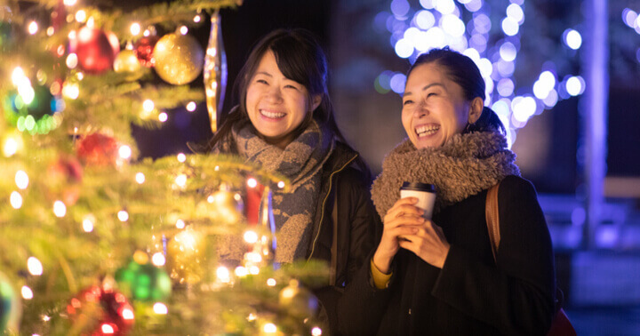 Two ladies standing in front of a lit Christmas tree