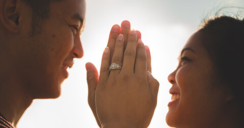 a couple smiling at each other, palm to palm