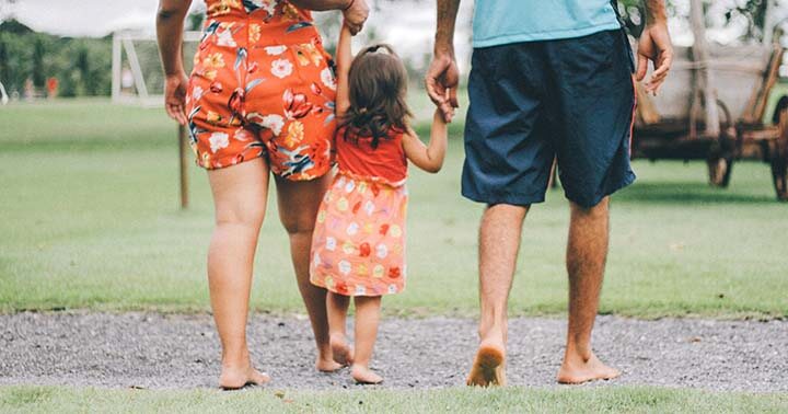 Family of three walking barefooted in a park