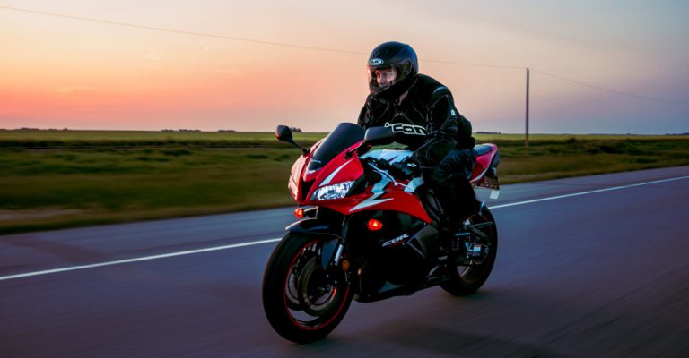 Lone motorcycle rider on the road with a sunset background