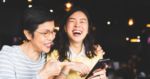 Mother and daughter laughing heartily at the phone