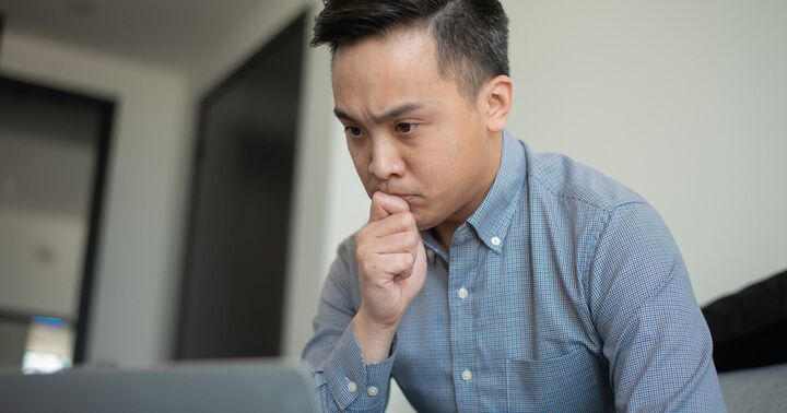 Man looking at laptop apprehensively