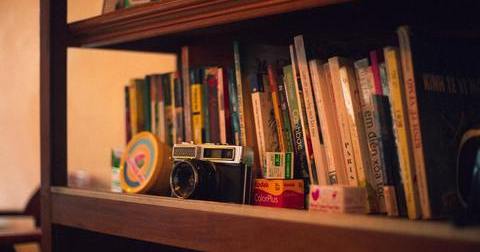 A collection of books and camera on a shelf