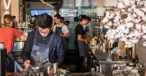 A barista making a cup of coffee in a busy cafe