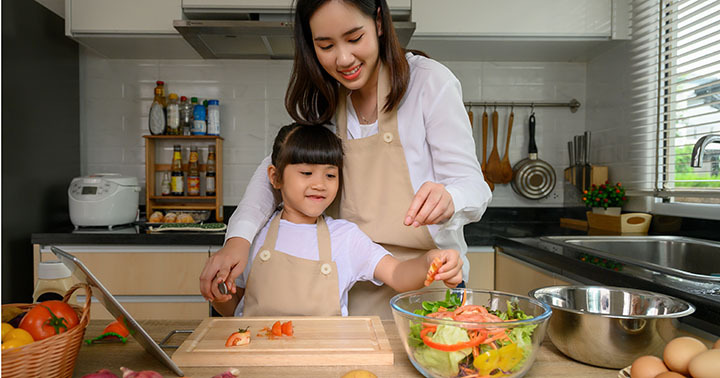 mother and daughter helping to making salad in kitchen