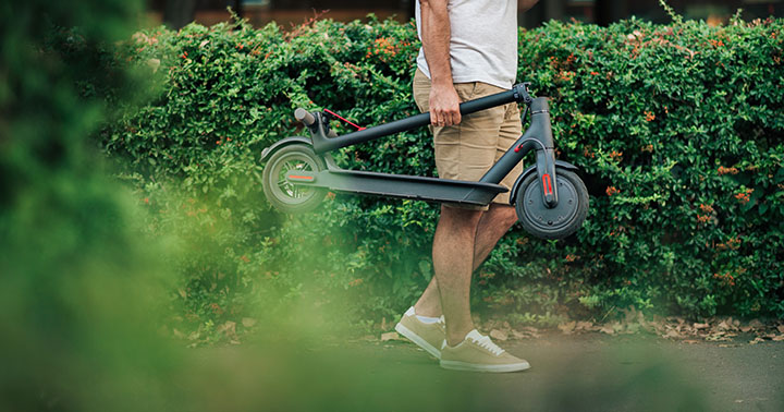 Eco transportation concepts. Man renting electric scooter, using smart phone in the park.