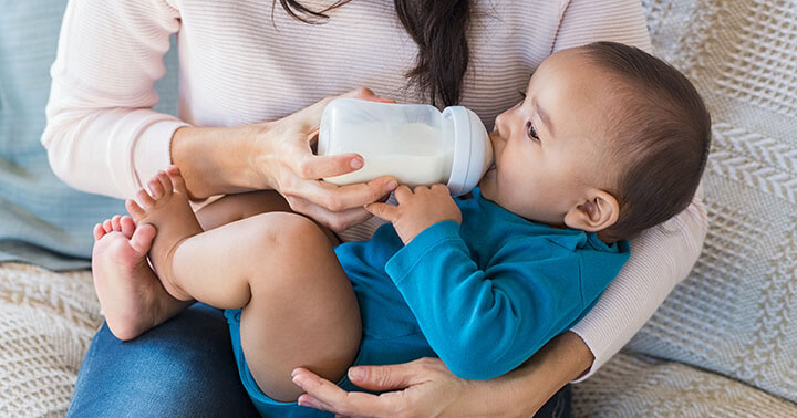 A woman feeding a bottle of milk to a baby in her arms