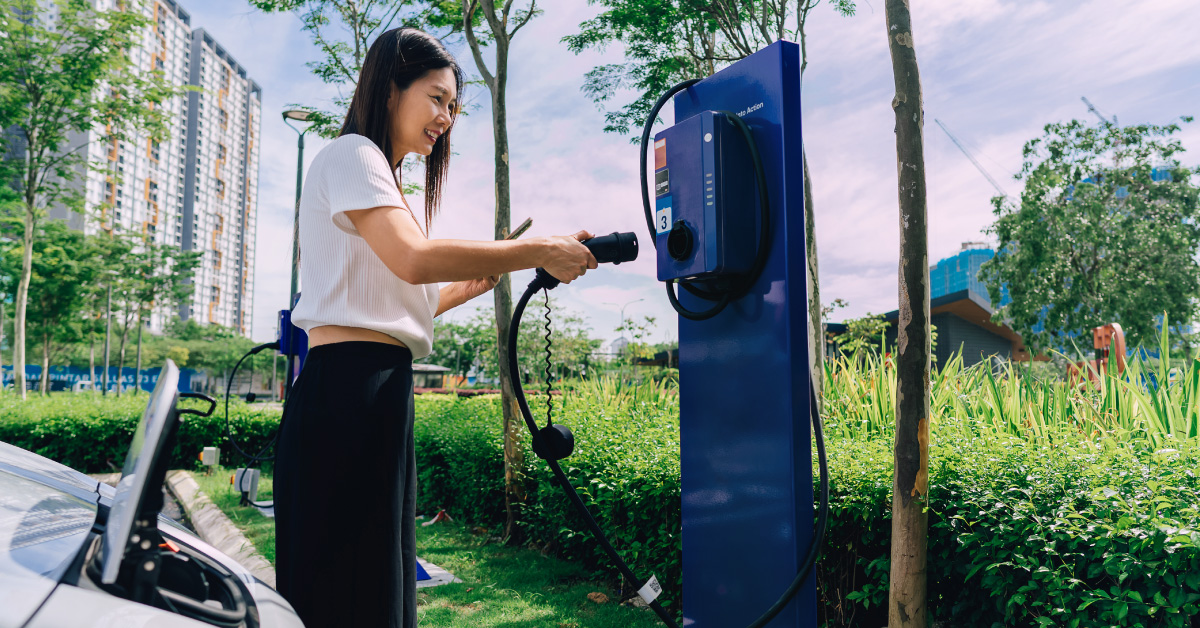woman-at-parking-lot-holding-an-ev-charger-plug