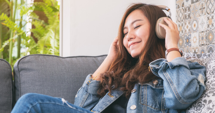 A young woman relaxing at home listening to the radio on a pair of headphones