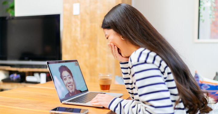 A woman laughing with her friend during a Zoom conference call