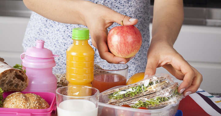 A mother preparing lunch boxes so her child can practise social distancing at school