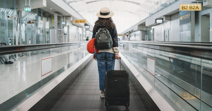 Female traveller pulling a luggage on a travelator in the airport