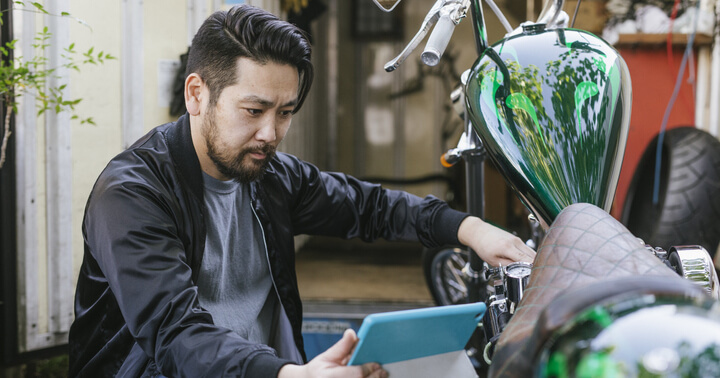 A rider fixing his motorcycle by watching a tutorial on an iPad