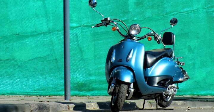 A vespa parked by the roadside