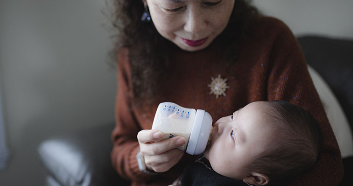 Grandmother feeding young infant