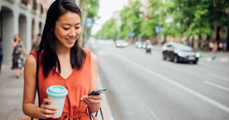 A lady holding a reusable cup on the street