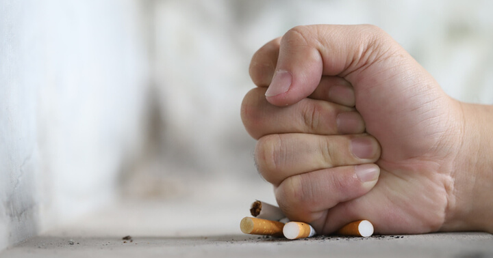 A hand crushing cigarettes as a symbol to quit smoking
