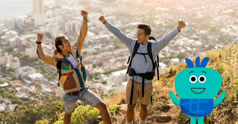 Two male friends, in full hiking gear, celebrating the success of them reaching their hiking destination together