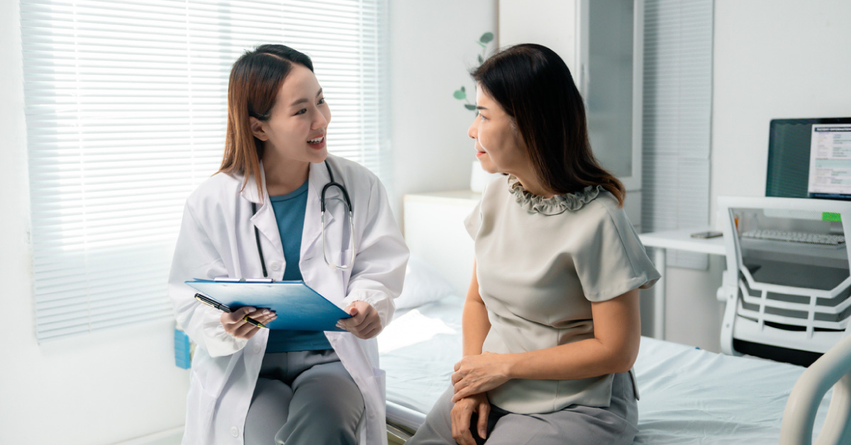 doctor-reviewing-medical-chart-while-conversing-with-seated-patient